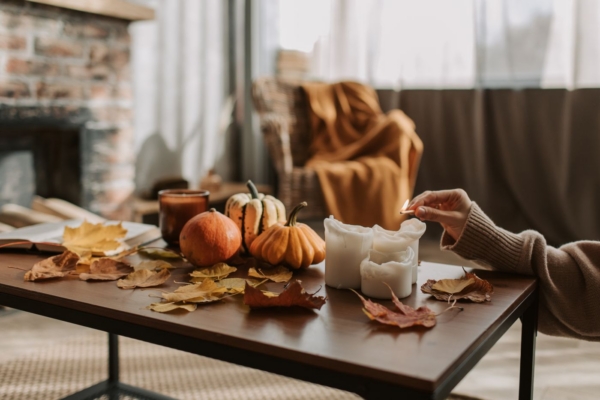 Herbstliche Deko mit Kürbissen, Laub und Kerzen auf einem Wohnzimmertisch