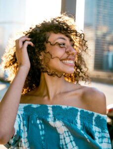 Lachende Frau mit Locken im warmen Sonnenlicht