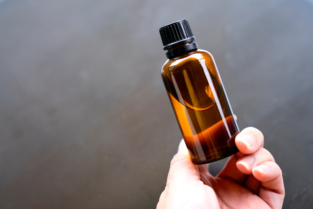 Hand hält eine markenfreie Braunglas-Flasche mit ätherischem Öl in der Manufaktur in Bunde