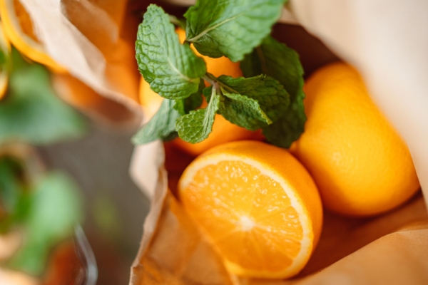 Frische Orangen und Minzzweige in einer Papiertüte